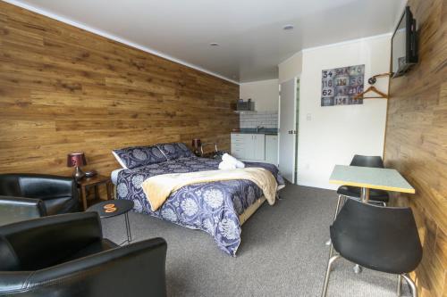 a bedroom with a bed and a wooden wall at New Plymouth TOP 10 Holiday Park in New Plymouth