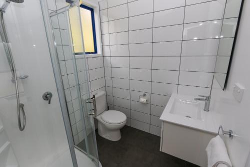 La salle de bains blanche est pourvue de toilettes et d'un lavabo. dans l'établissement New Plymouth TOP 10 Holiday Park, à New Plymouth