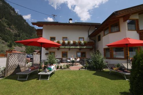 patio z krzesłami i parasolami przed budynkiem w obiekcie Alpenpension Elferblick w Neustift im Stubaital