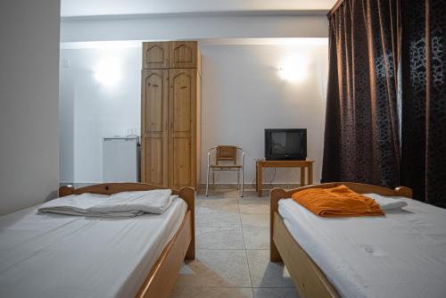 two beds in a room with a tv and a bedroom at La Papu și Maia in Eforie Sud