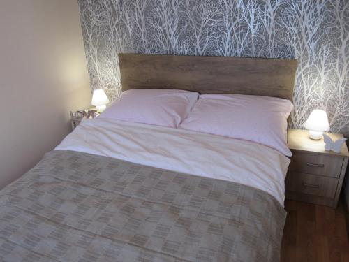 1 cama en un dormitorio con 2 lámparas en una mesa en Manta Apartamenty, en Sianożęty