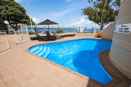 a large blue swimming pool next to a building at The Village Resort in Taupo