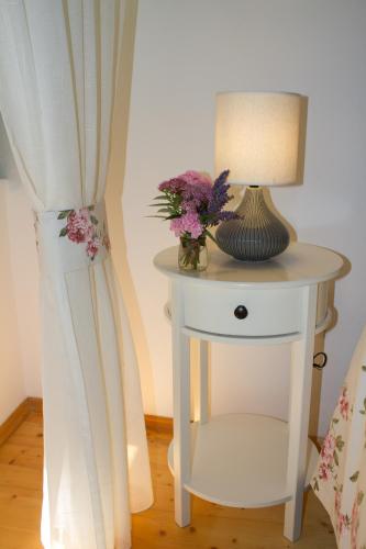 a white table with a lamp and flowers on it at House Corte dei Matte' in Rovinj