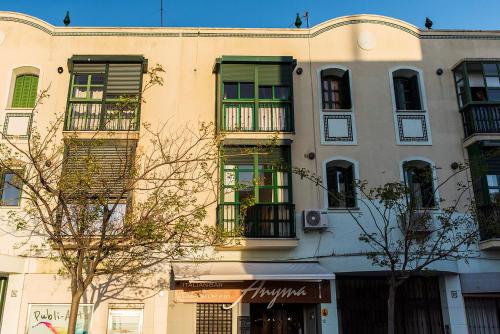 a tall building with green windows on a street at Suite Mirando al Guadiana in Ayamonte