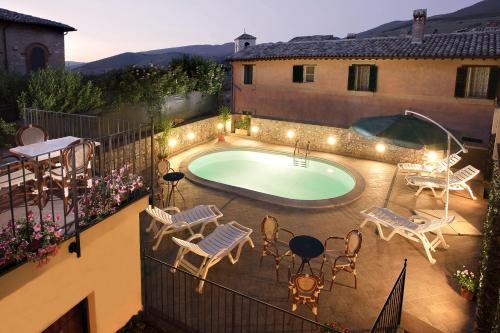 un patio con piscina, sillas y mesa en Antica Dimora alla Rocca, en Trevi