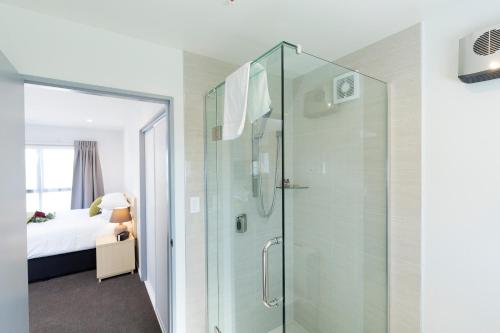 a bathroom with a glass shower with a bed at 239 on Lincoln Motel in Christchurch