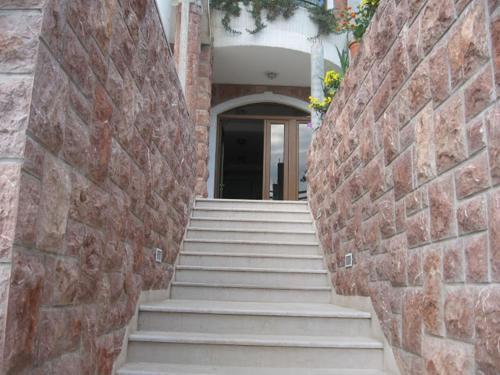 a staircase leading to a building with a brick wall at Apartments and Rooms Levantin Inn in Sveti Stefan