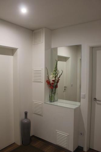 a vase with flowers in a room with a mirror at Manuel Tiago Pereira in Braga