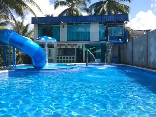 una piscina con un tobogán de agua azul frente a una casa en Hotel La Cascada - Lago Agrio, en Nueva Loja