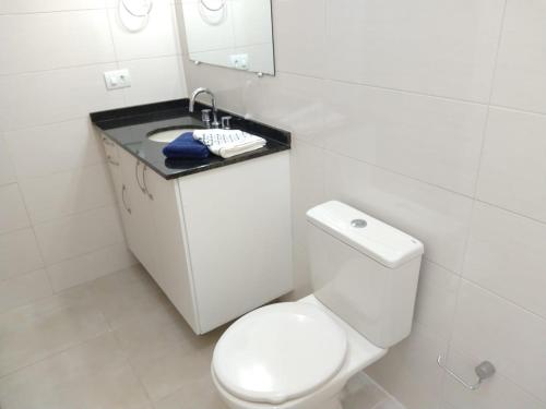 y baño con aseo blanco y lavamanos. en Casa Curitiba 120m² (1 Suíte e 2 Quartos) com garagem em condomínio, en Curitiba