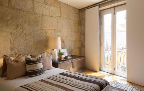 um quarto com uma cama com uma parede de pedra em Casa Castanha em Porto