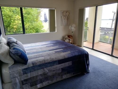 a bedroom with a large bed and large windows at Harbour Views Omokoroa in Omokoroa Beach