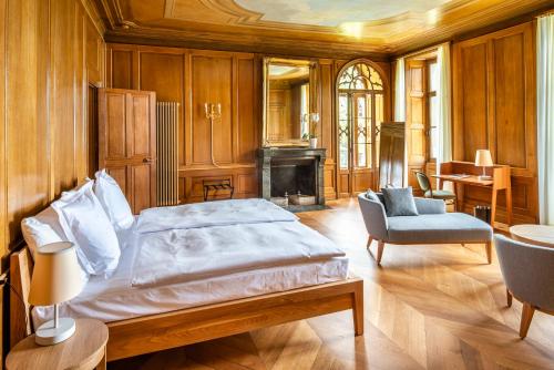 Schloss Schadau - Swiss Historic Hotel في ثون: غرفة نوم بسرير وكرسي ومدفأة