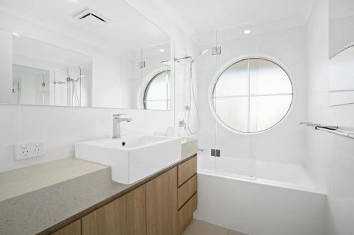 Kirra Palms Holiday Apartments في غولد كوست: حمام أبيض مع حوض ومرآة