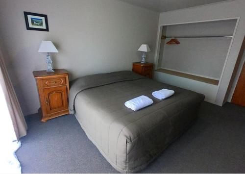 a bedroom with a bed with two white towels on it at Ruapehu Mountain Motel & Lodge in Ohakune
