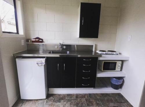 a small kitchen with a sink and a microwave at Ruapehu Mountain Motel & Lodge in Ohakune