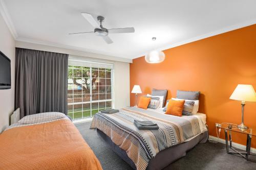 a bedroom with two beds with orange walls and a window at City Two Apartment in Mount Gambier