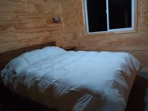 Bett in einem Zimmer mit Fenster in der Unterkunft Cabañas Reflejo de Luna in Castro