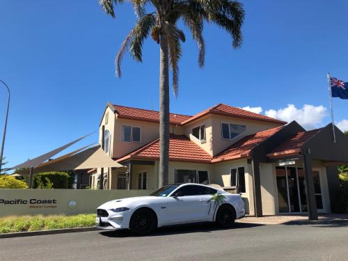 a white car parked in front of a house at Pacific Coast Motor Lodge in Whakatane