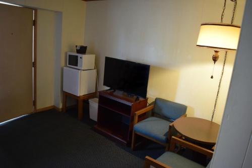 a room with a tv and a chair and a table at Mid-City Motel in Sault Ste. Marie