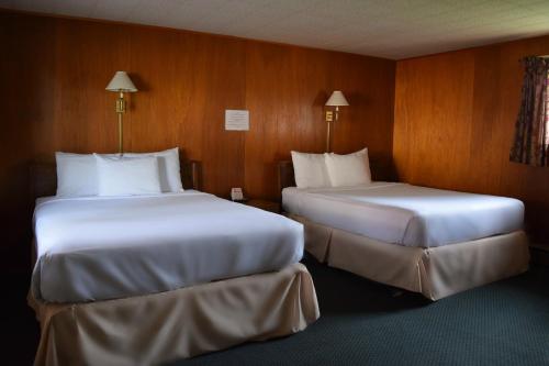two beds in a room with wooden walls at Mid-City Motel in Sault Ste. Marie