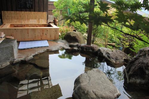 a pond in a garden with rocks at Yufuin-Sanso Waremokou in Yufuin