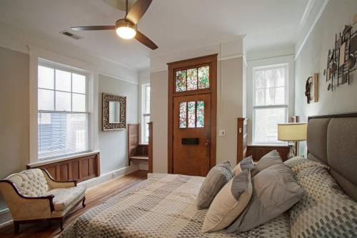 a bedroom with a bed and a chair and windows at 101 E Waldburg - Cozy Cottage just off of Forsyth Park in Savannah
