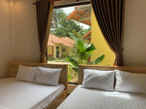 two beds in a room with a window at Sun & Wind Paradise Bungalow in Phú Quốc