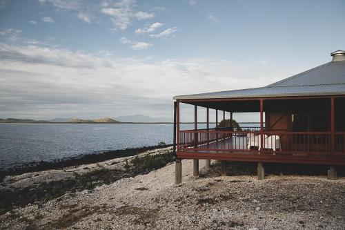 una casa con balcone accanto a una cassa d'acqua di Camp Island Lodge a Guthalungra