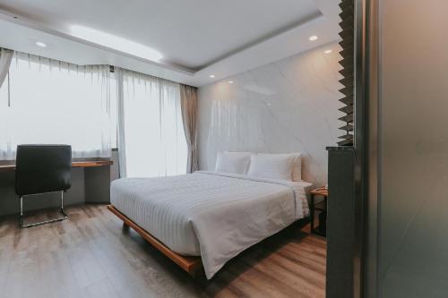 a bedroom with a bed and a desk and a window at Bangkok City Link Hotel in Bangkok