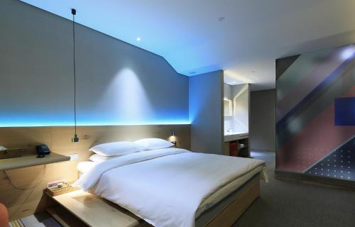 a bedroom with a large bed with a blue ceiling at EBO Hotel (Hangzhou West Lake) in Hangzhou