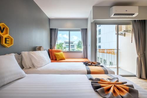 um quarto de hotel com duas camas e uma varanda em Beehive Boutique Hotel Phuket em Phuket