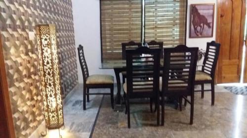 uma sala de jantar com uma mesa, cadeiras e um candeeiro em Mulberry Guest House F-10 em Islamabad