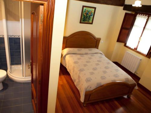 a small bedroom with a bed and a bathroom at Goikoetxe Baserria in Zeanuri