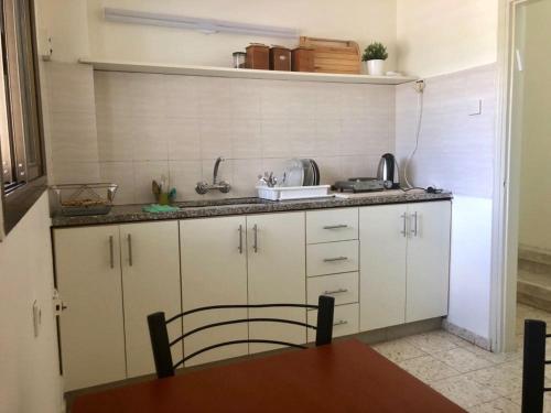 a kitchen with white cabinets and a sink at Tamar's House in Arad