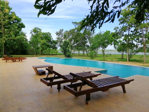 a pool with picnic tables and benches next to it at Breezy Lake in Tissamaharama
