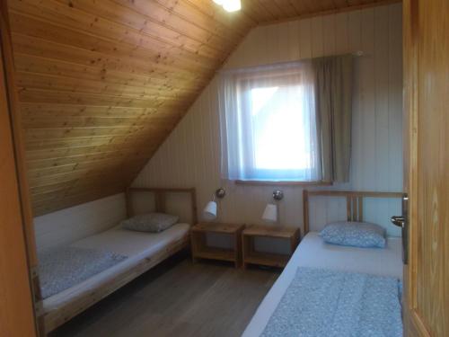 two beds in a room with a window at Domki letniskowe U Joli - Jolanta Potrykus in Władysławowo