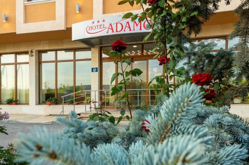 a building with a sign and plants in front of it at Adamo Hotel in Varna City