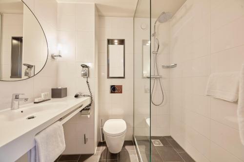 a bathroom with a shower and a toilet and a sink at Carlton Square Hotel in Haarlem