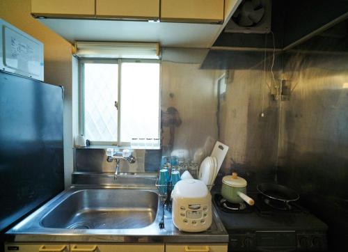 cocina pequeña con fregadero y fogones en RHK guest house, en Tokio