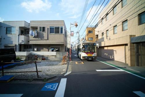 un autobús conduciendo por una calle de la ciudad con edificios en RHK guest house, en Tokio