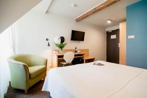 a bedroom with a bed and a chair and a desk at Hotel Czarna Róża in Toruń