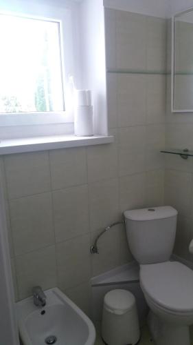 a white bathroom with a toilet and a sink at Hotel Gold in Poznań