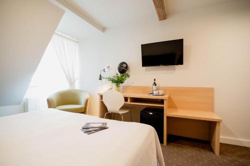 a hotel room with a desk and a tv at Hotel Czarna Róża in Toruń