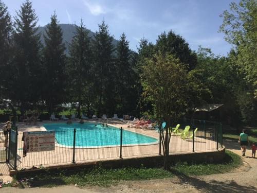 uma piscina num parque com cadeiras e árvores em Le Vallon em Ispagnac