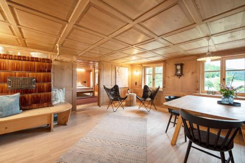 een woonkamer met een houten plafond en een tafel en stoelen bij WÄLDERHAUS Apartments in Schwarzenberg im Bregenzerwald