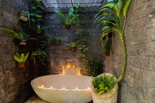 a bathroom with a bath tub and potted plants at Taman Kesari Villas in Sanur