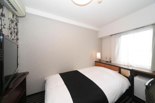 a bedroom with a black and white bed and a window at APA Hotel Wakayama in Wakayama