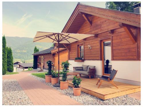 a wooden deck with a bench and an umbrella at Dorfchalets Kaprun in Kaprun