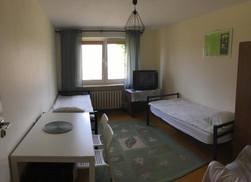 mały pokój z 2 łóżkami i stołem w obiekcie Noclegi Tulipan w Koninie